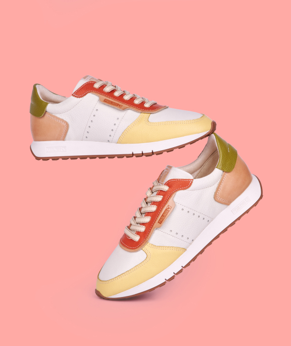 Women's white sneakers on a pink background