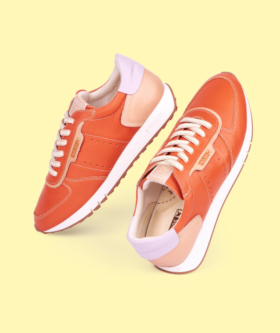 Women's orange sneakers on a yellow background